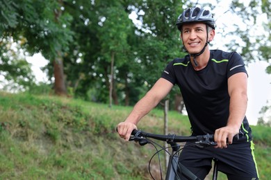 Photo of Happy man riding bicycle in park, space for text. Healthy lifestyle