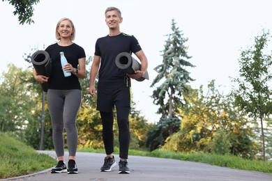 Photo of Happy couple with bottle of water and fitness mats in park