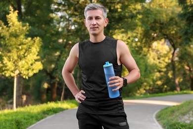 Man in sportswear with bottle of water in park