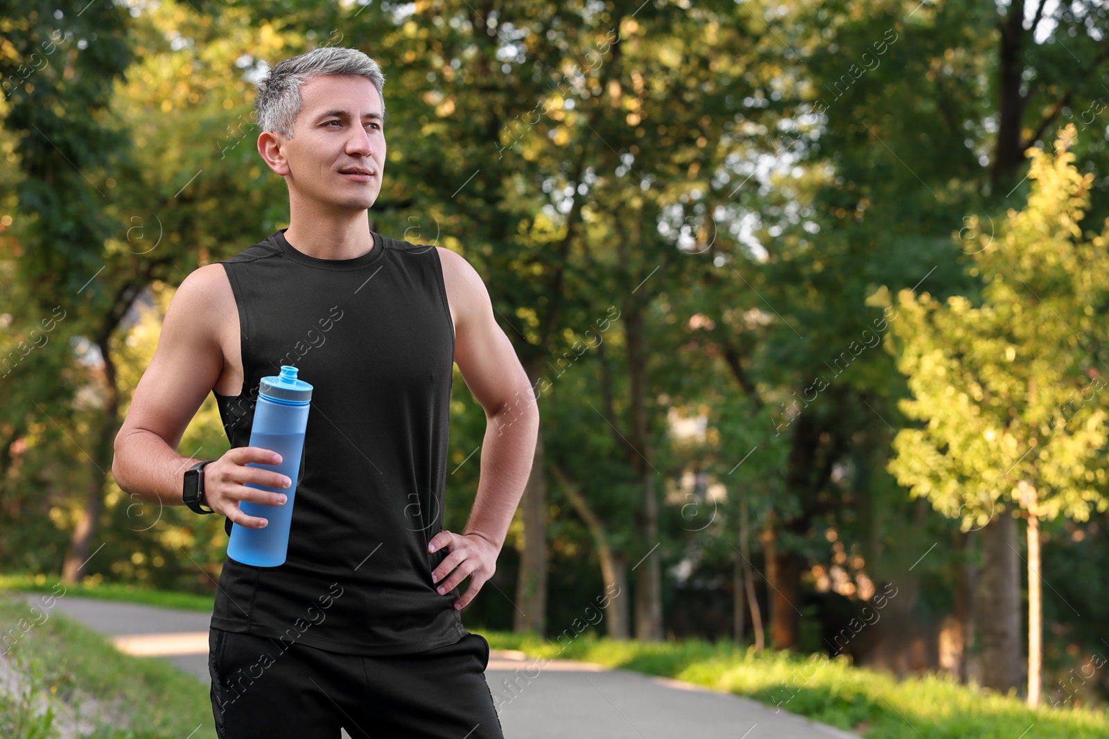 Photo of Man in sportswear with bottle of water in park, space for text