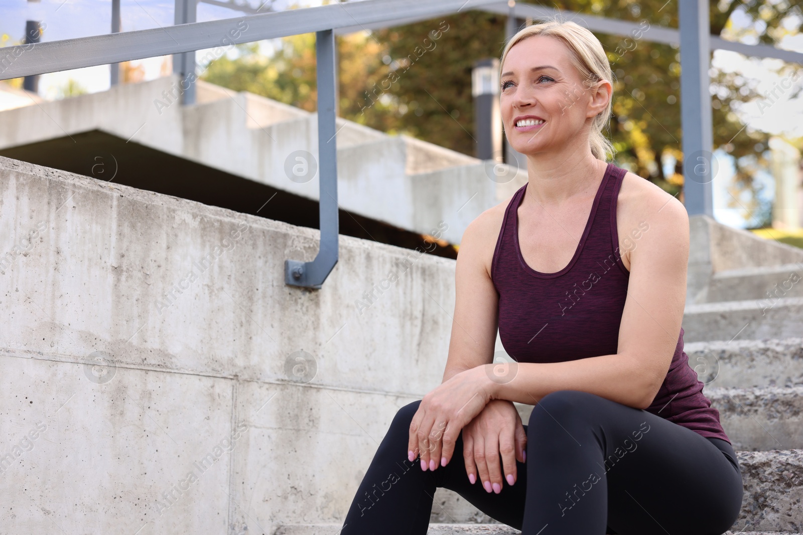 Photo of Smiling woman in sportswear on steps outdoors