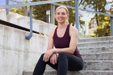 Smiling woman in sportswear on steps outdoors