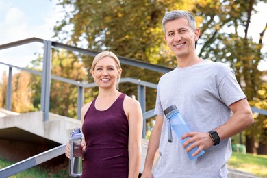 Photo of Happy couple with bottles of water in park