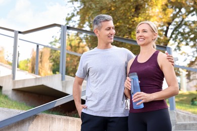 Happy couple with bottle of water in park