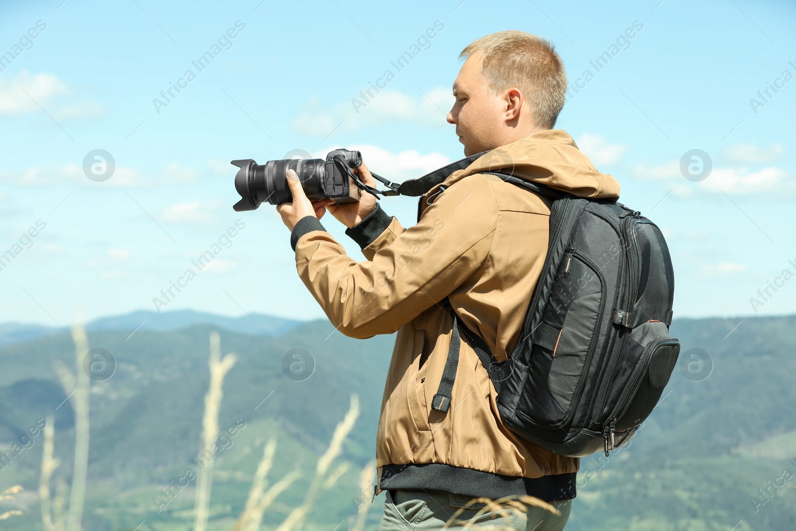 Photo of Photographer with backpack and camera taking picture of beautiful mountains