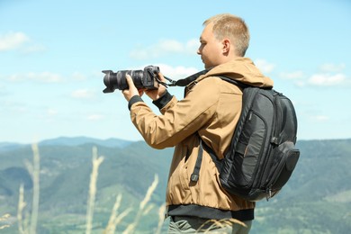 Photo of Photographer with backpack and camera taking picture of beautiful mountains