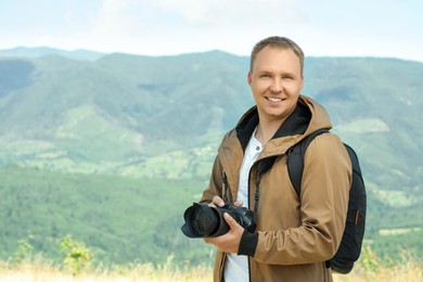 Photographer with backpack and camera in mountains. Space for text