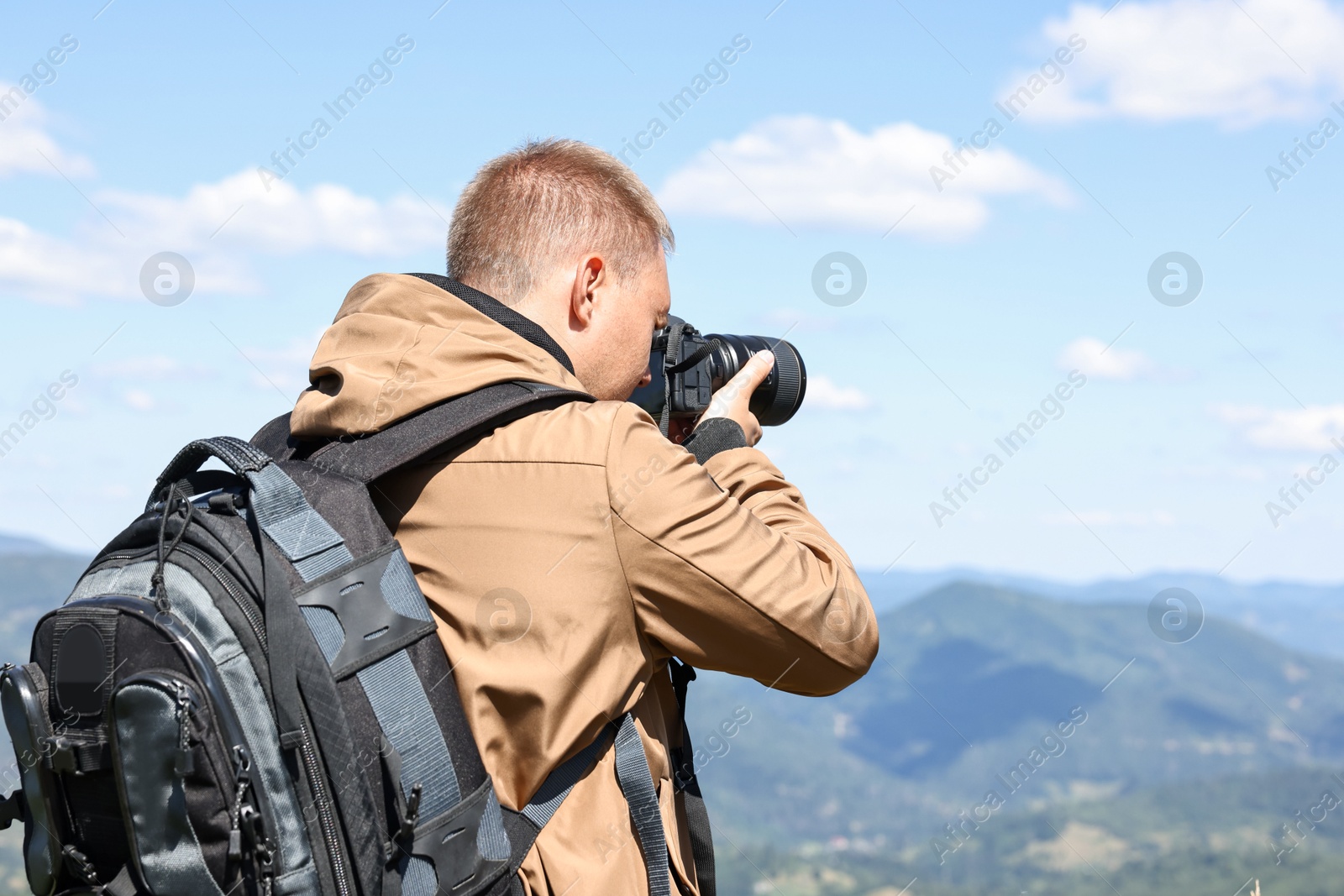 Photo of Photographer with backpack and camera taking picture of beautiful mountains. Space for text