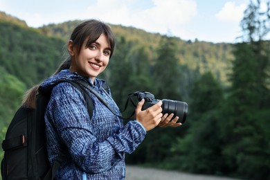 Photo of Smiling photographer with backpack and camera outdoors