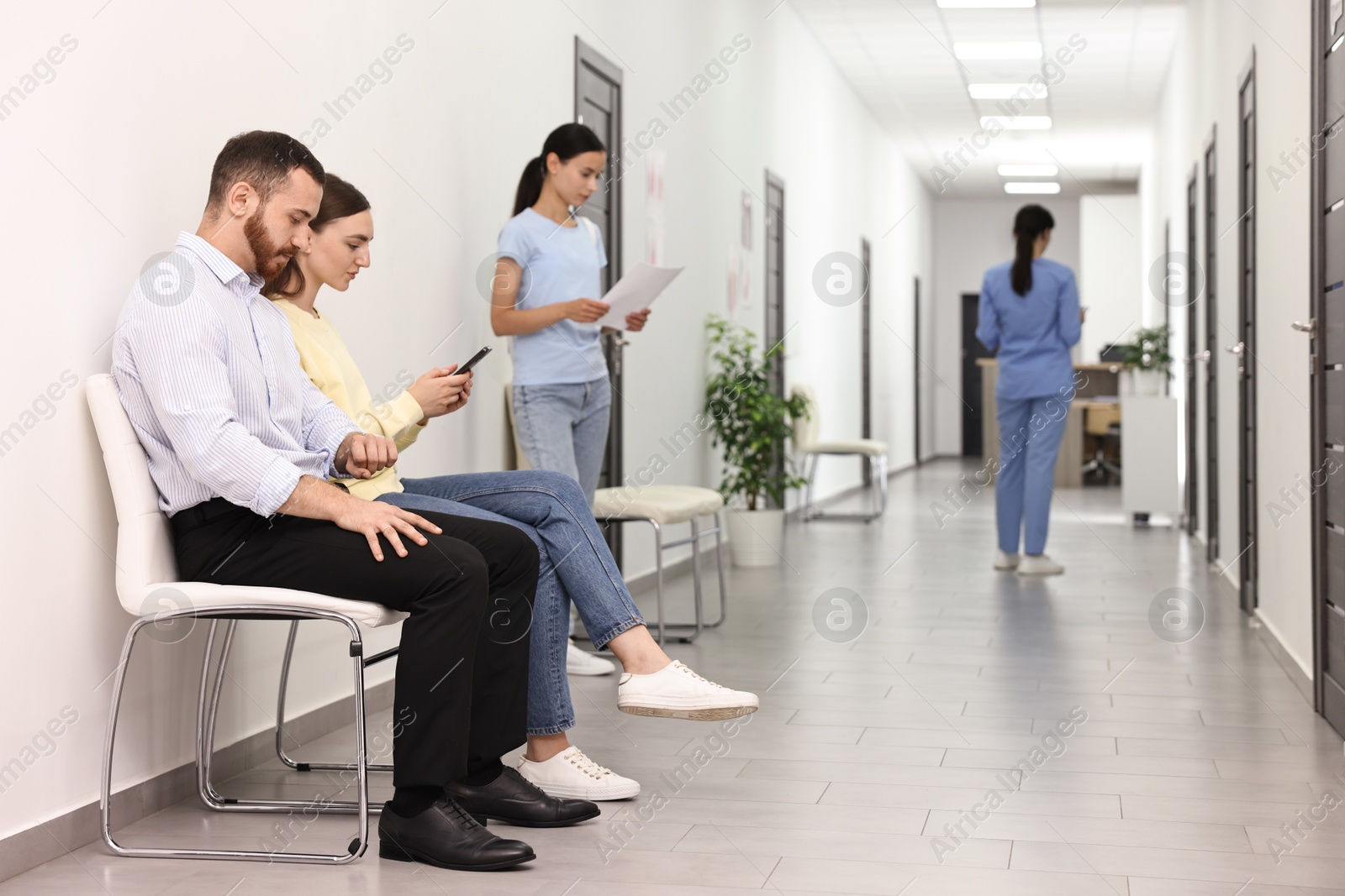 Photo of Patients waiting for appointment and doctor in hospital hallway, selective focus