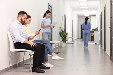 Photo of Patients waiting for appointment and doctor in hospital hallway, selective focus