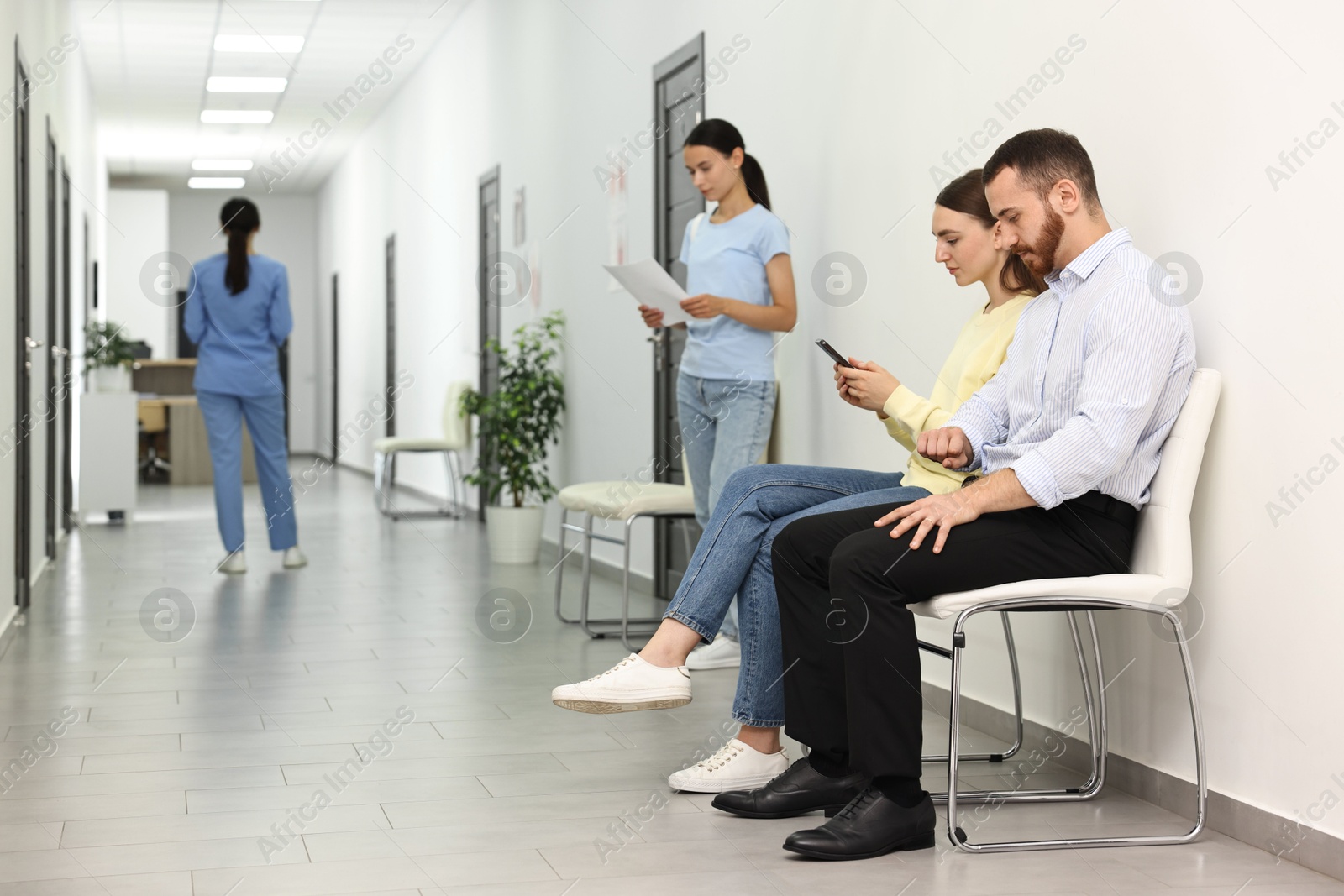 Photo of Patients waiting for appointment and doctor in hospital hallway, selective focus