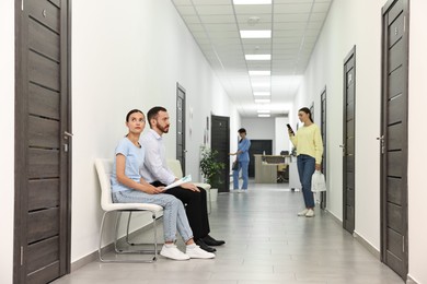 Patients waiting for appointment and doctor in hospital hallway, selective focus