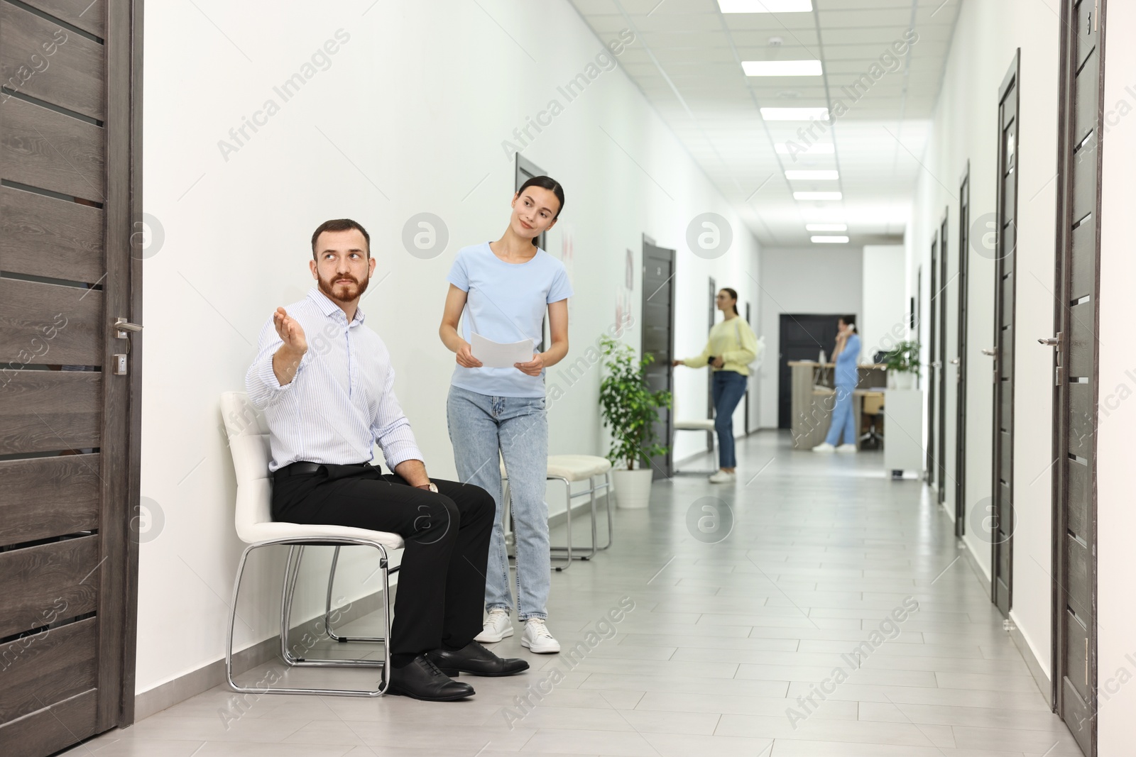 Photo of Patients waiting for appointment and doctor in hospital hallway, selective focus