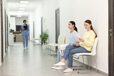 Patients waiting for appointment and doctor in hospital hallway, selective focus