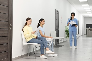 Patients waiting for appointment and doctor in hospital hallway, selective focus