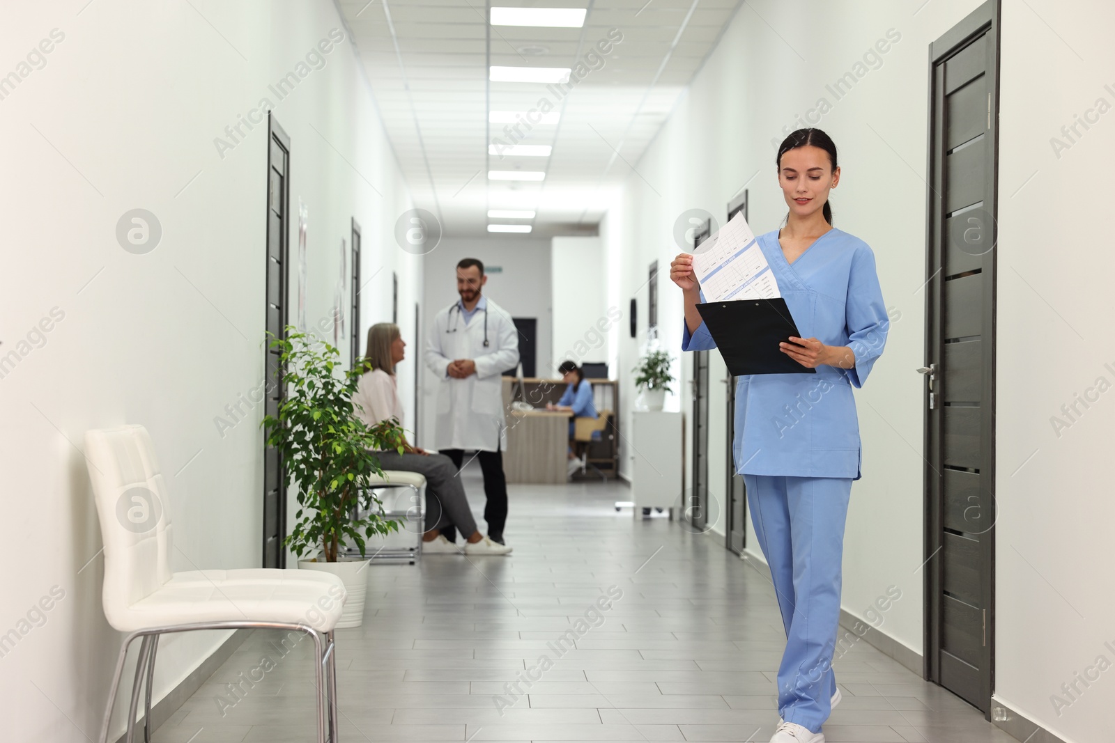 Photo of Nurse with clipboard in hospital hallway, selective focus