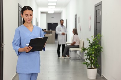 Photo of Nurse with clipboard in hospital hallway, selective focus