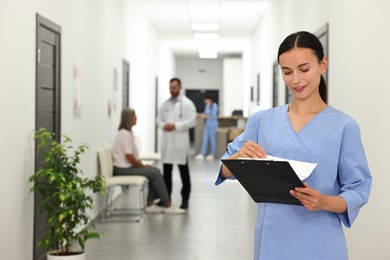 Nurse with clipboard in hospital hallway, selective focus