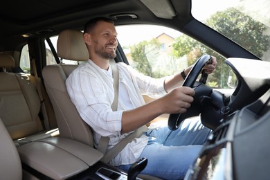 Smiling man holding steering wheel while driving car