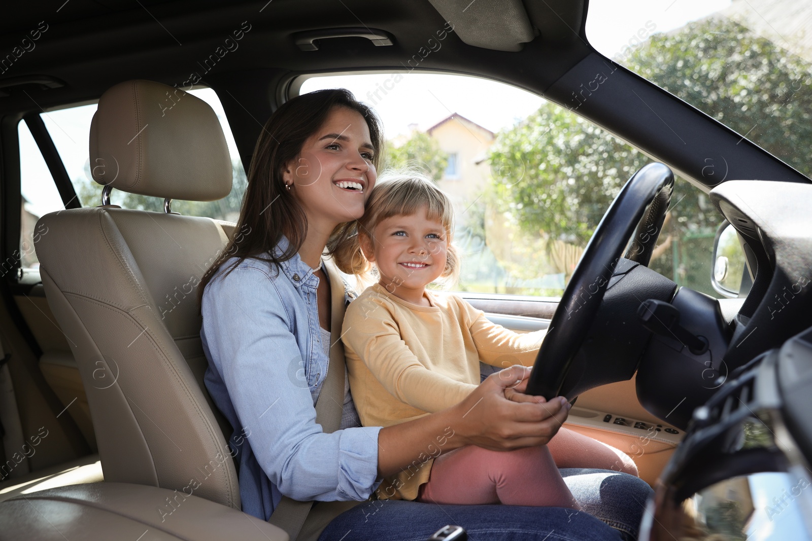 Photo of Happy woman with her daughter holding steering wheel inside car