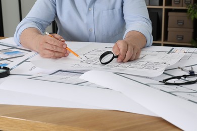 Architect working with project at wooden table in office, closeup