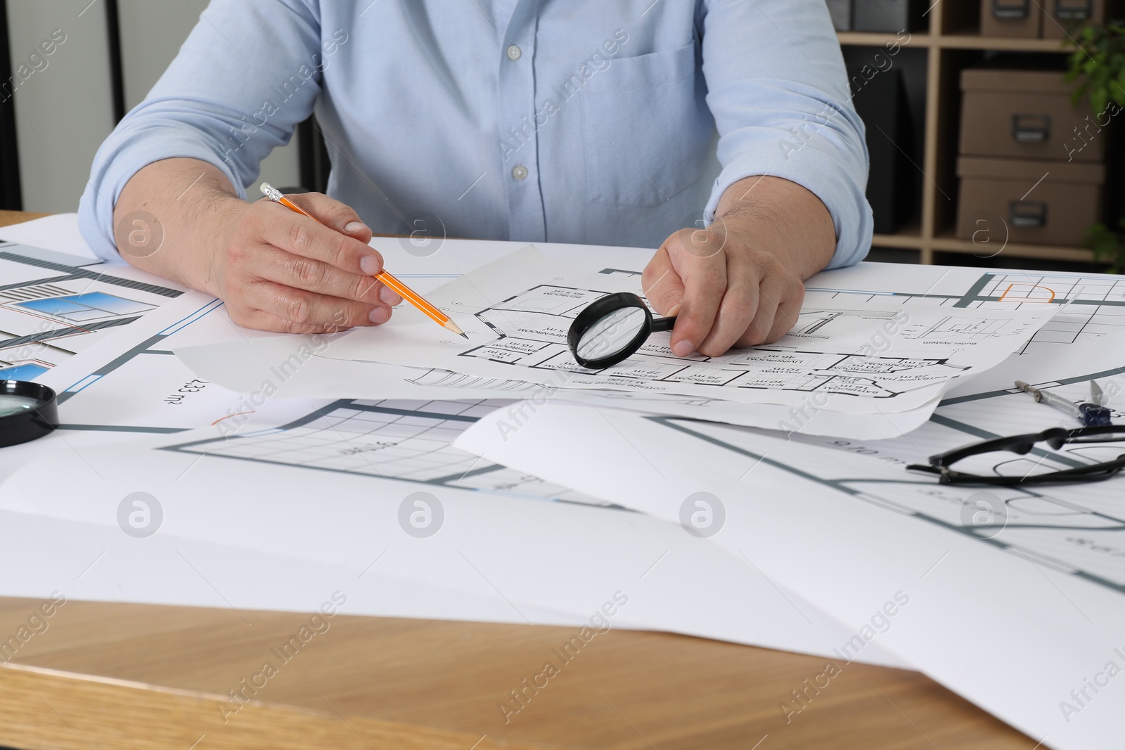 Photo of Architect working with project at wooden table in office, closeup