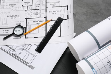 Photo of Different architectural drawings, ruler, pencil and magnifying glass on grey textured table, flat lay