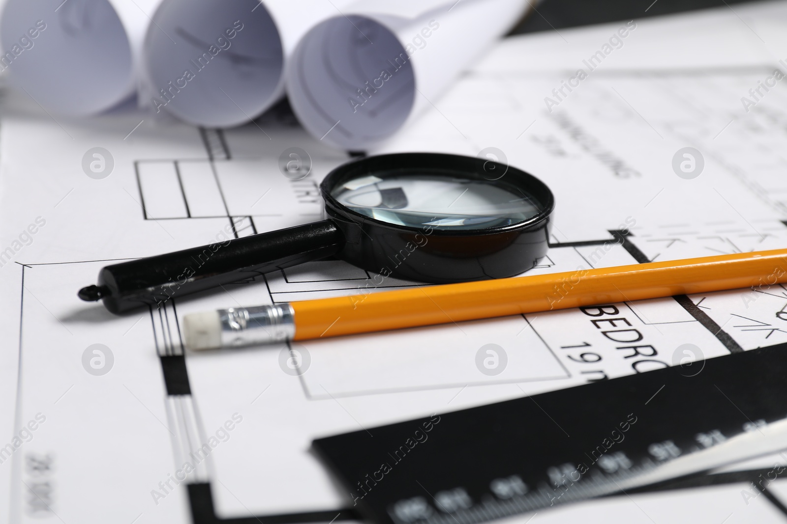 Photo of Different architectural drawings, pencil, ruler and magnifying glass on table, closeup