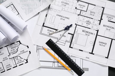 Photo of Different architectural drawings, divider, ruler and pencil on table, flat lay