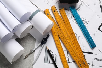 Photo of Different engineering drawings and tools on grey textured table, flat lay