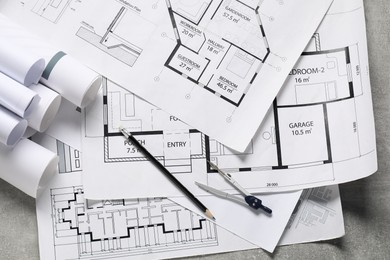 Photo of Different engineering drawings, pencil and divider on grey textured table, flat lay