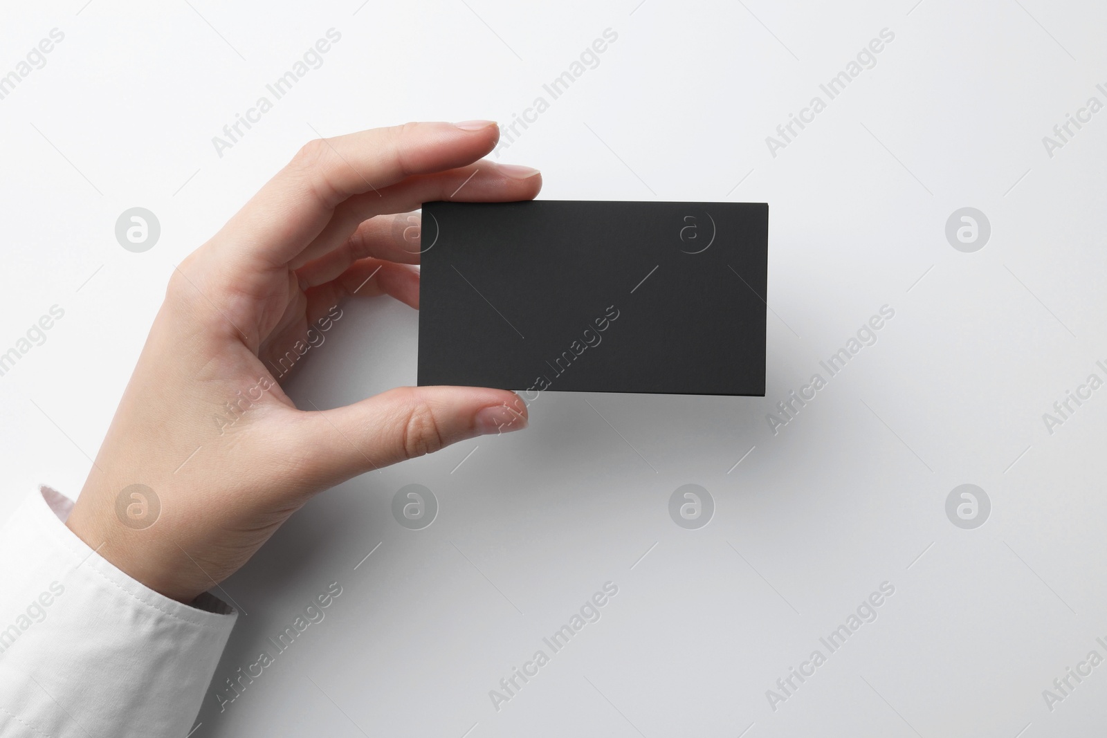 Photo of Woman with blank business card on light grey background, closeup. Mockup for design