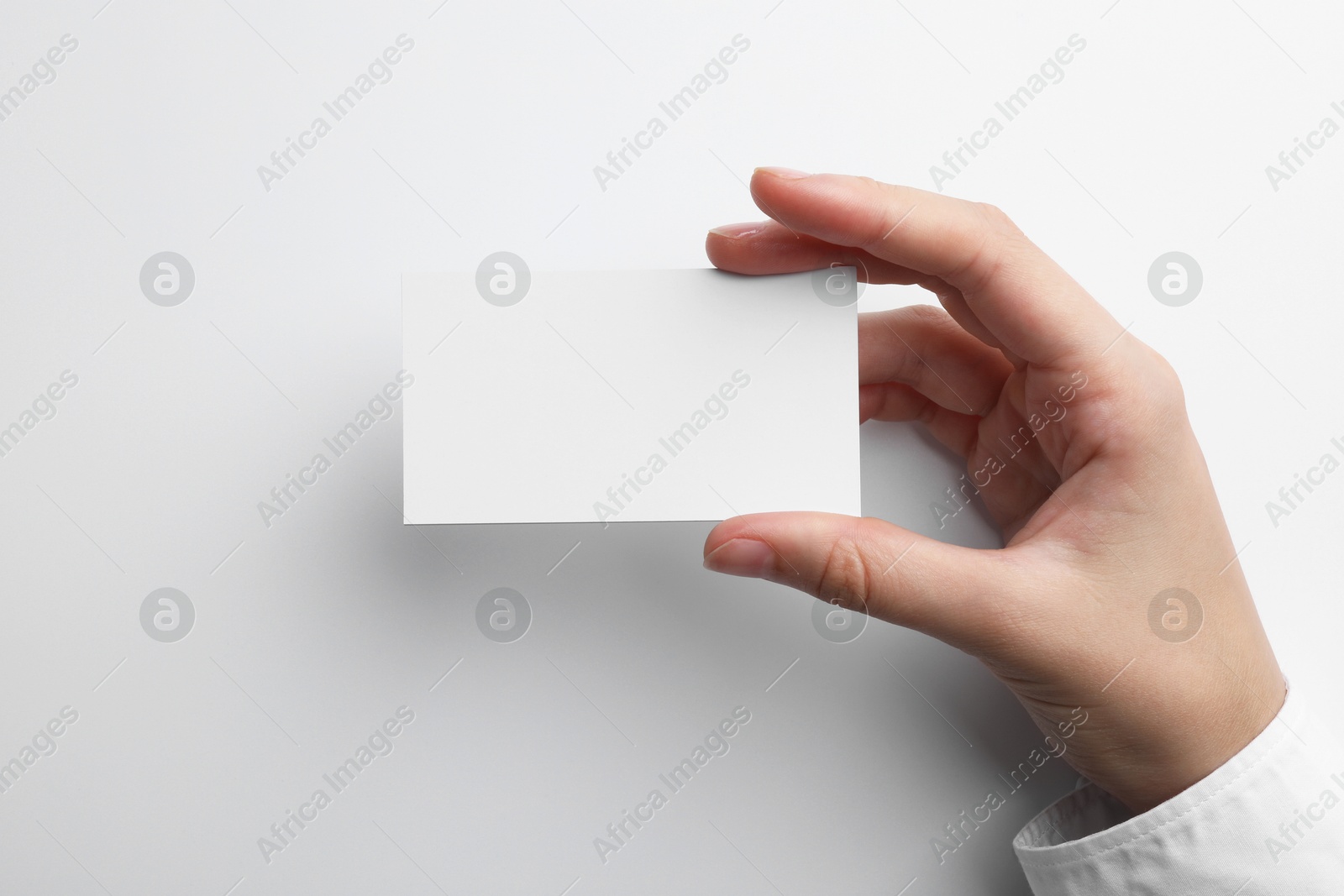 Photo of Woman with blank business card on light grey background, closeup. Mockup for design