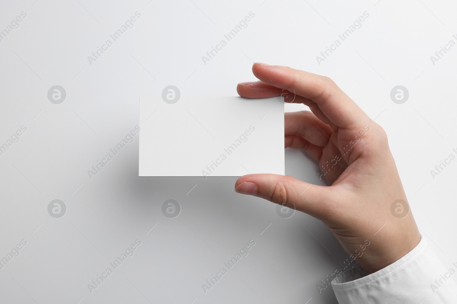 Photo of Woman with blank business card on light grey background, closeup. Mockup for design