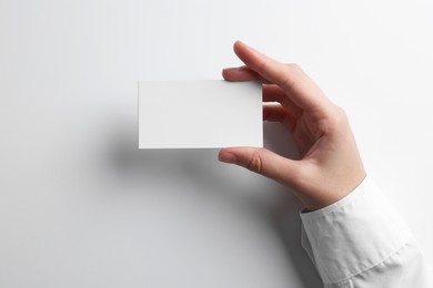 Photo of Woman with blank business card on light grey background, closeup. Mockup for design