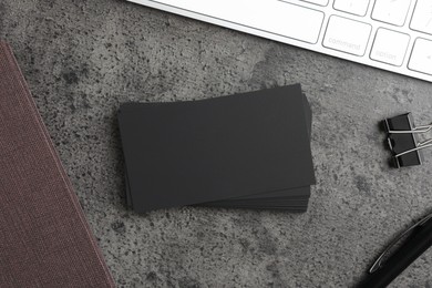 Photo of Blank business cards, keyboard and binder clip on grey textured table, flat lay. Mockup for design