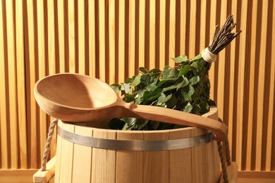 Photo of Sauna equipment. Bucket, ladle and oak whisk against wooden wall