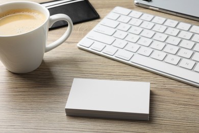 Photo of Blank business cards, coffee and keyboard on wooden table. Mockup for design