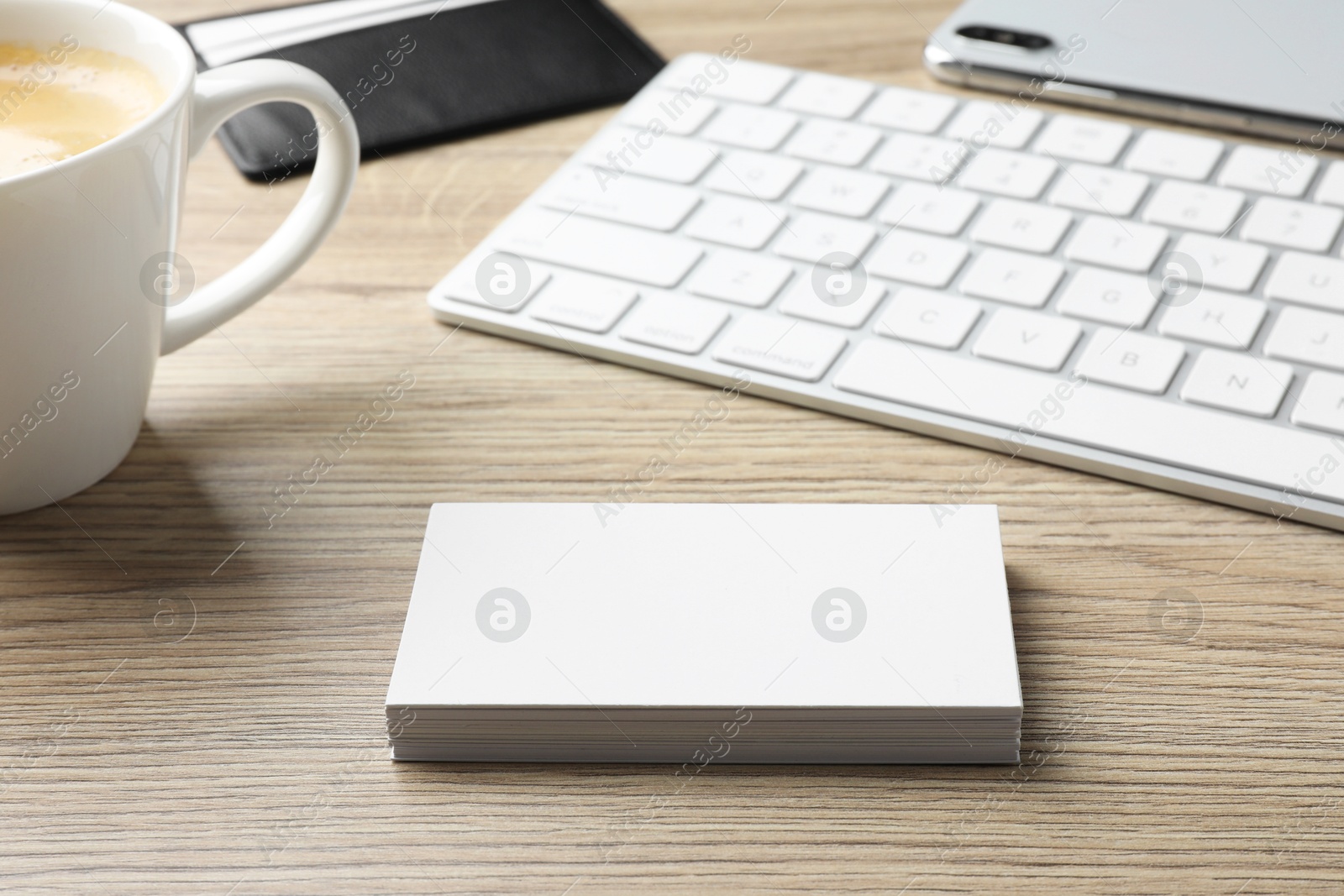 Photo of Blank business cards, coffee and keyboard on wooden table. Mockup for design