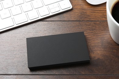 Photo of Blank business cards and keyboard on wooden table. Mockup for design