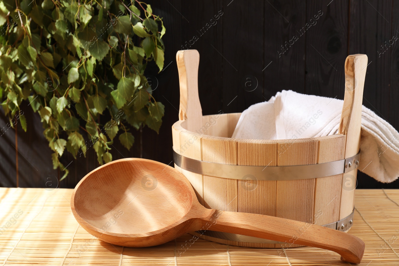 Photo of Sauna equipment. Bucket, towel and ladle on bamboo bench