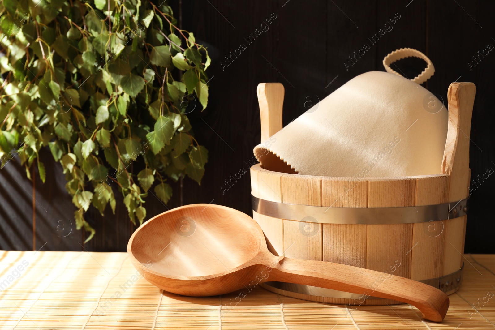 Photo of Sauna equipment. Bucket, felt wool hat and ladle on bamboo bench