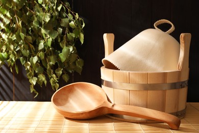 Sauna equipment. Bucket, felt wool hat and ladle on bamboo bench