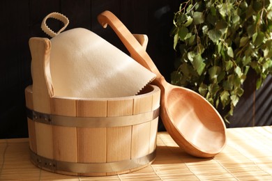 Photo of Sauna equipment. Bucket, felt wool hat and ladle on bamboo bench