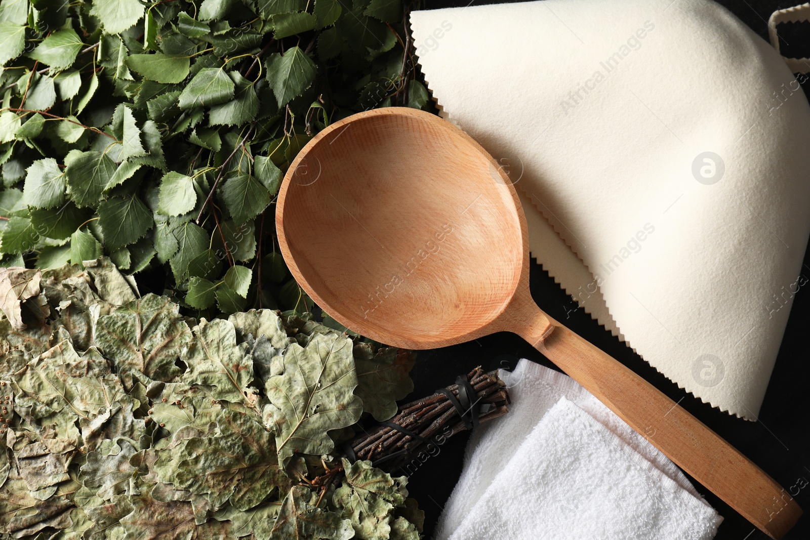 Photo of Sauna whisks, felt wool hat and wooden ladle on table, flat lay