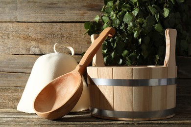 Photo of Sauna equipment. Bucket, felt wool hat and ladle on wooden surface