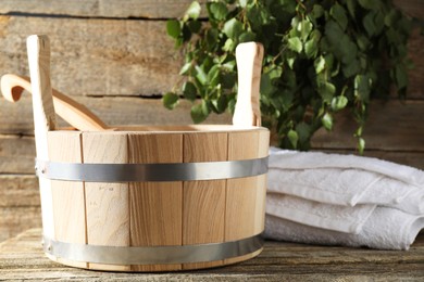 Photo of Sauna equipment. Bucket with ladle and towel on wooden surface