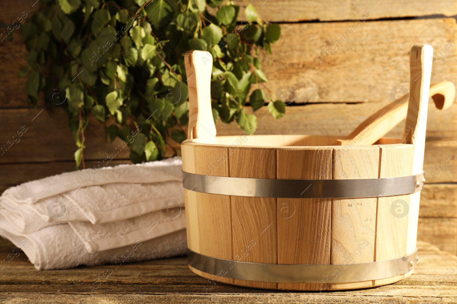 Photo of Sauna equipment. Bucket with ladle and towel on wooden surface