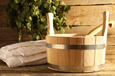 Photo of Sauna equipment. Bucket with ladle and towel on wooden surface